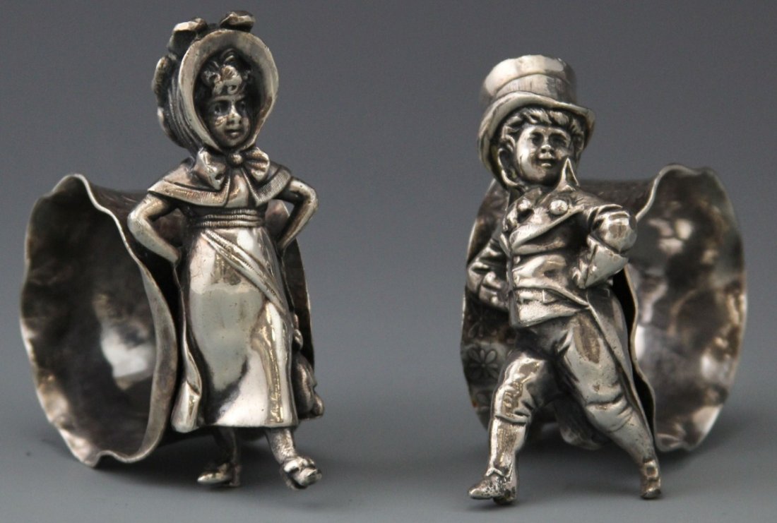 (2) VICTORIAN SILVER PLATED FIGURAL NAPKIN RINGS: (2) VICTORIAN SILVER PLATED FIGURAL NAPKIN RINGS Pair of Victorian silver plated figural napkin rings; Dapperly dressed young boy and girl akimbo, unmarked. Weight 209.4g total Size: 3"