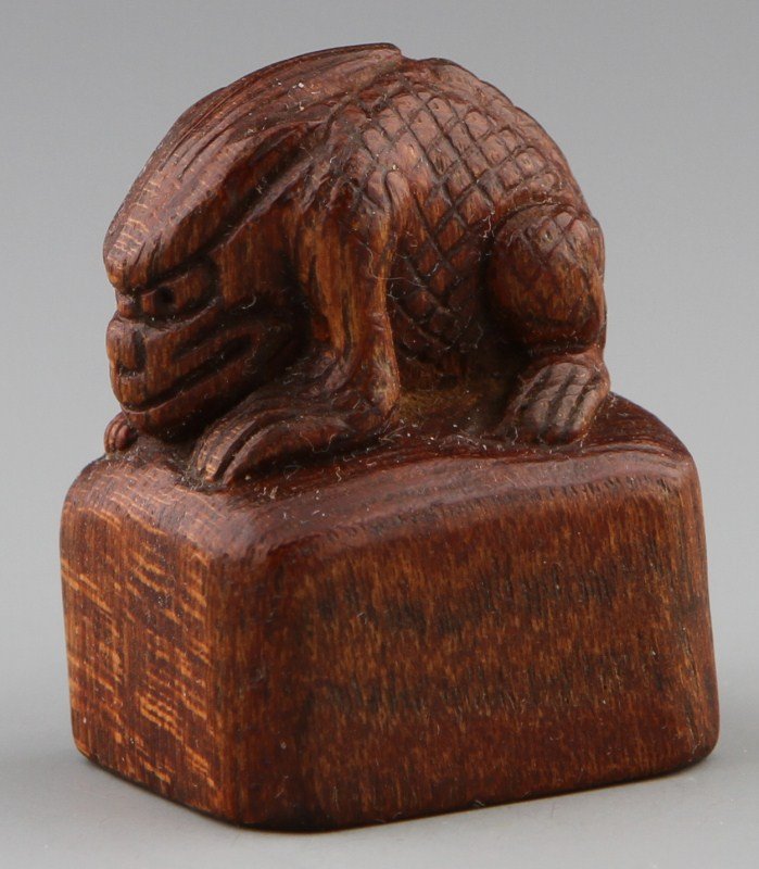 JAPANESE CARVED WOOD NETSUKE / CHOP: JAPANESE CARVED WOOD NETSUKE / CHOP Japanese carved wood netsuke/ chop surmounted by a crouching Oni. Weight: 11g Size: 1.5 x 1.625"