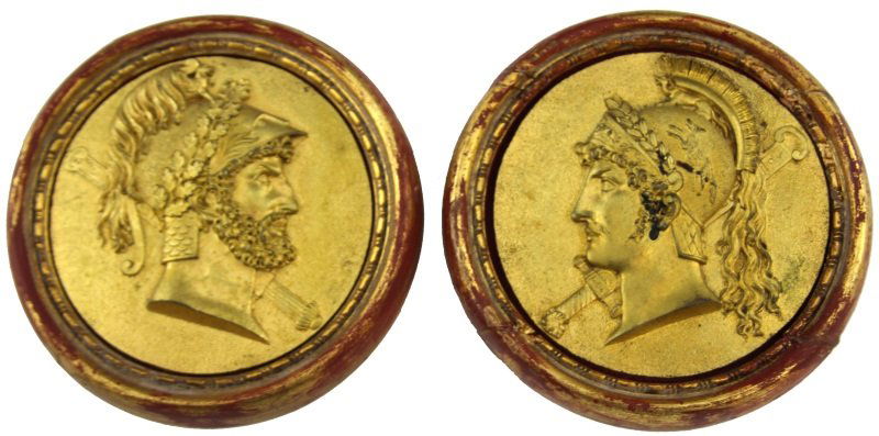 (2) FRAMED RELIEFS OF ROMAN SOLDIERS: (2) FRAMED RELIEFS OF ROMAN SOLDIERS A pair of reliefs of Roman soldiers. The reliefs are done in metal that is painted gold, and are framed in round gold and red frames. Wire is attached to the back