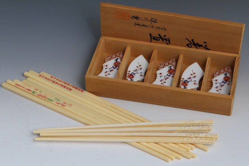 CARVED IVORY CHOPSTICKS W/ PORCELAIN HOLDERS: CARVED IVORY CHOPSTICKS W/ PORCELAIN HOLDERS Two pair ivory chopsticks, 9", with carved ends. Five porcelain Amari style Japanese chopstick rests in the shape of fans, comes with wooden storage box. A