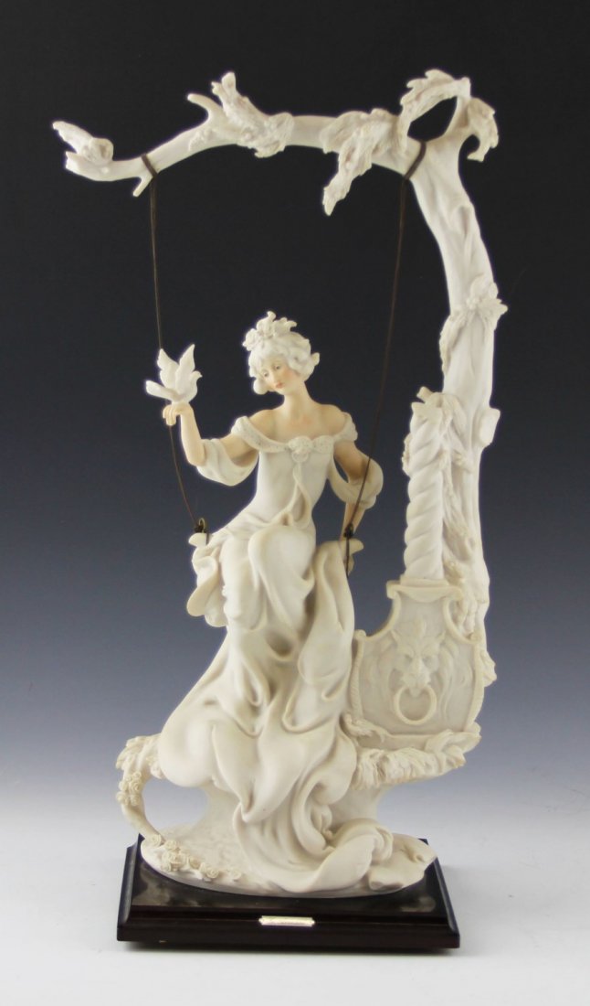 COMPOSITE CAPODIMONTE LADY ON SWING FIGURE: COMPOSITE CAPODIMONTE LADY ON SWING FIGURE Composite Capodimonte figure on a lady on a swing with a bird on her right hand. Swing chains are made of base metal and the remainder of the piece is compos