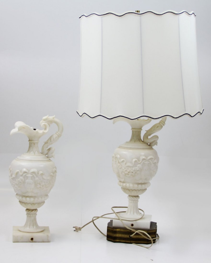 (2) ALABASTER PITCHER LAMPS: (2) ALABASTER PITCHER LAMPS Lot of two alabaster pitcher form lamps; decorated with floral relief and figural phoenix or hawk handle. One lamp sits on a brass base. Sizes: 18" (without base or lightin