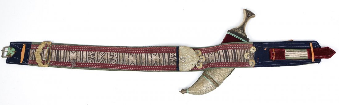 MIDDLE EASTERN JAMBIYA KNIFE WITH BELT: MIDDLE EASTERN JAMBIYA KNIFE WITH BELT Jambiya knife with silver wrapped sheath and wooden handle, comes with gilt embroidered belt with silver accents. Weight: 1.6lbs Size: 41" belt, 14" Jambiya