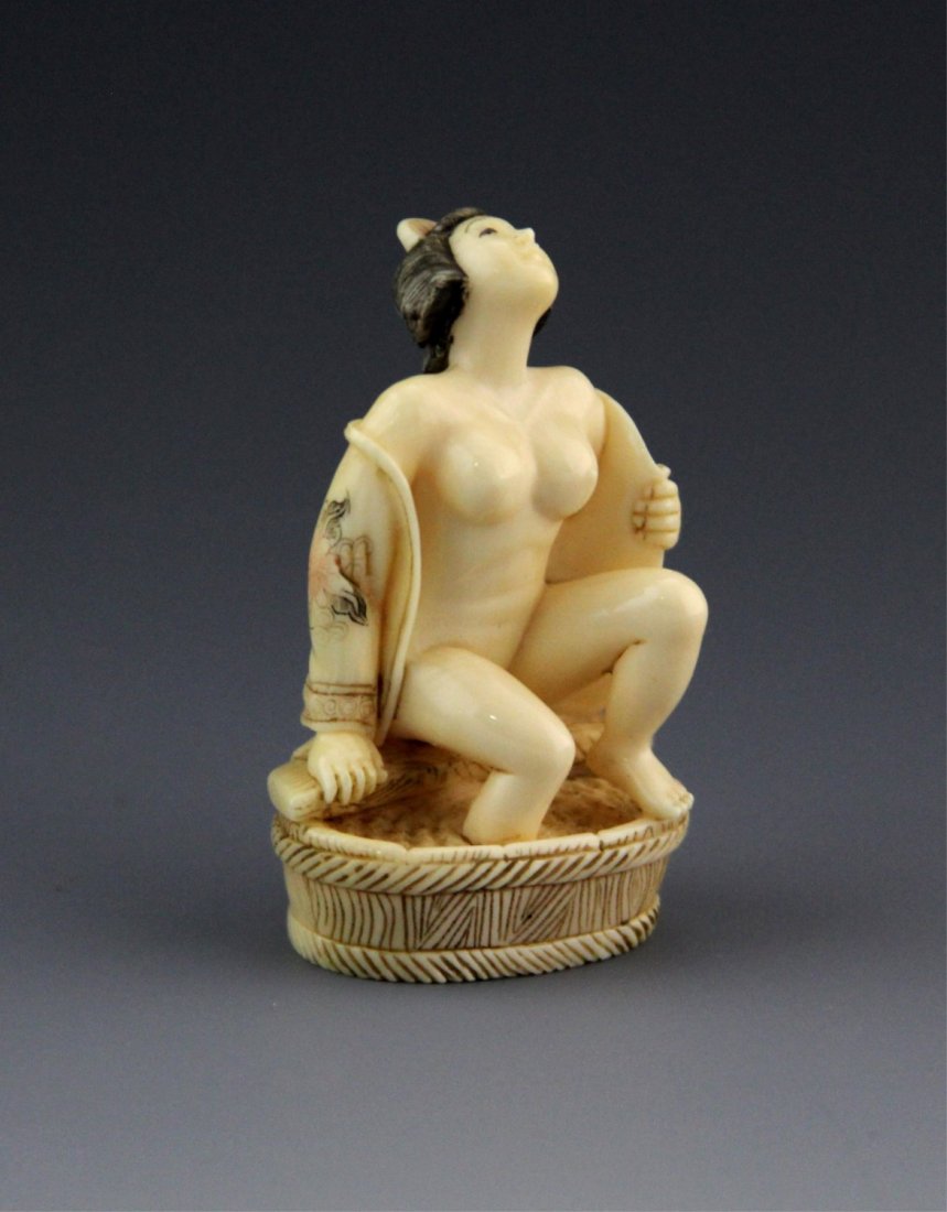 JAPANESE CARVED IVORY NETSUKE BATHING GEISHA: JAPANESE CARVED IVORY NETSUKE BATHING GEISHA Japanese carved ivory netsuke featuring seated Geisha in floral robe, open in front. Bottom features signature. Weight: 18.5 g Size: 2"