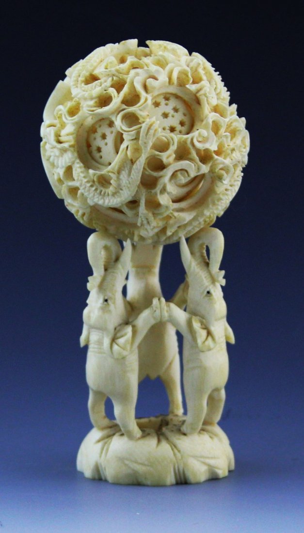 ANTIQUE CARVED IVORY PUZZLE BALL WITH STAND: ANTIQUE CARVED IVORY PUZZLE BALL WITH STAND Antique Chinese carved ivory puzzle ball, eight plus layers with dragon motif, stand is comprised of three elephants holding hands. Weight: 146.5 g Size: ba