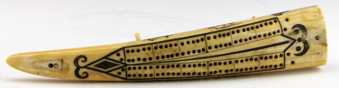 WALRUS IVORY CRIBBAGE BOARD WITH SCRIMSHAW: WALRUS IVORY CRIBBAGE BOARD WITH SCRIMSHAW Walrus ivory cribbage board with scrimshaw details around the holes and a village scene on the base. The sides also have decorative elements, including some 