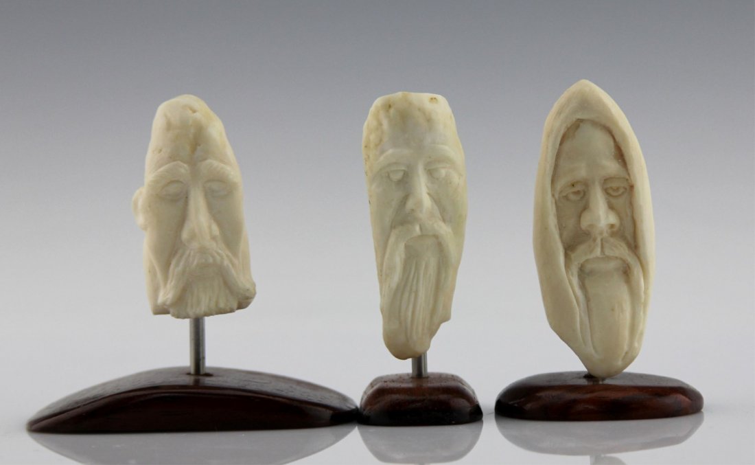(3) INUIT CARVED MARINE IVORY FACES ON STANDS: (3) INUIT CARVED MARINE IVORY FACES ON STANDS Lot of three Inuit carved marine ivory faces, each dowel mounted to wood base. Weight: 97.7g total including bases Size: ~3"