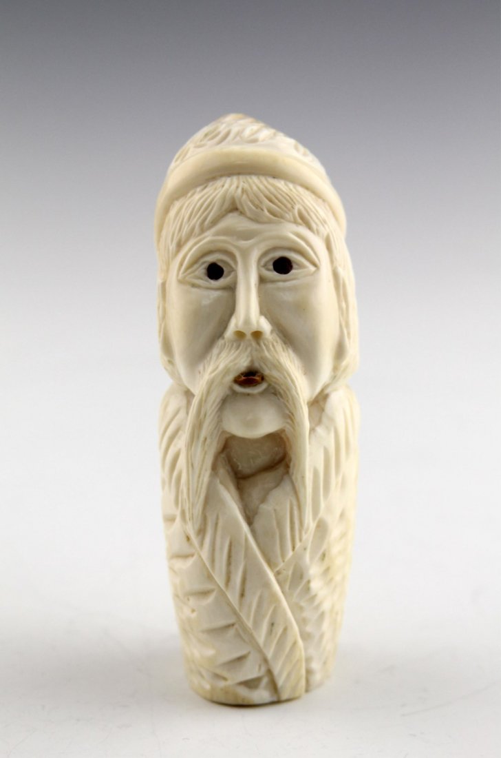INUIT IVORY WHALE TOOTH FIGURE OF MAN: INUIT IVORY WHALE TOOTH FIGURE OF MAN Fully carved Inuit ivory whale tooth depicting man sticking his tongue out; fossilized ivory and cabochon elements. Weight: 224.3g Size: 4.25"