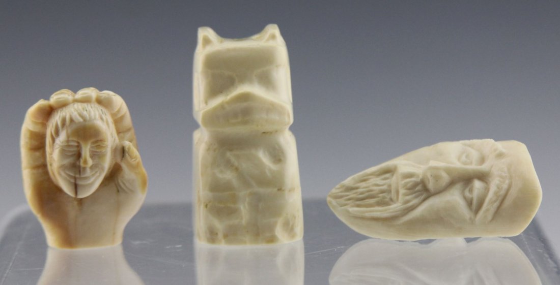 (2) WALRUS IVORY CARVED ITEMS: (2) WALRUS IVORY CARVED ITEMS Lot of three walrus ivory items; Includes mythic totem creature, 1.75", and two Inuit carved faces 1.5" - 2", one nested in a hand and the other with two faces. Weight: 6