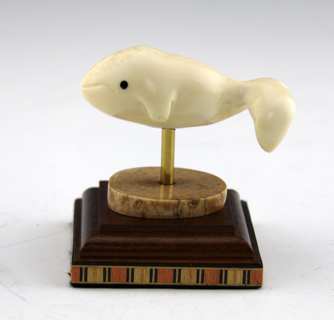CARVED WALRUS IVORY BABY WHALE ON BASE: CARVED WALRUS IVORY BABY WHALE ON BASE Carved walrus ivory baby whale, dowel mounted to fossilized bone/ivory cross section and wood base. Weight: 112g including base Size: 3 x 3"