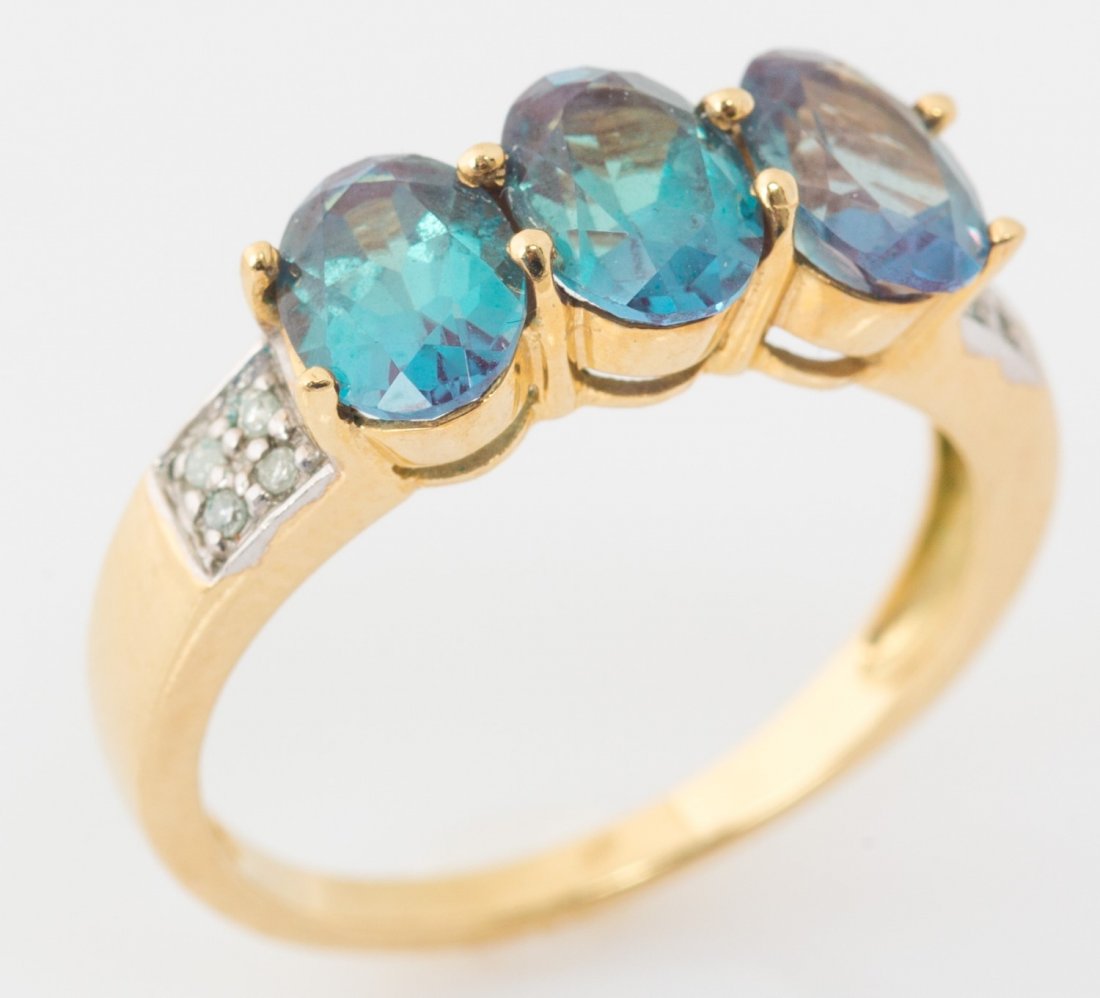 LADIES THREE STONE SYNTHETIC ALEXANDRITE STONE: LADIES THREE STONE SYNTHETIC ALEXANDRITE STONE Ladies three stone alexandrite ring with diamond accents, set in 14k yellow gold. Weight: 2.8g Size: 7
