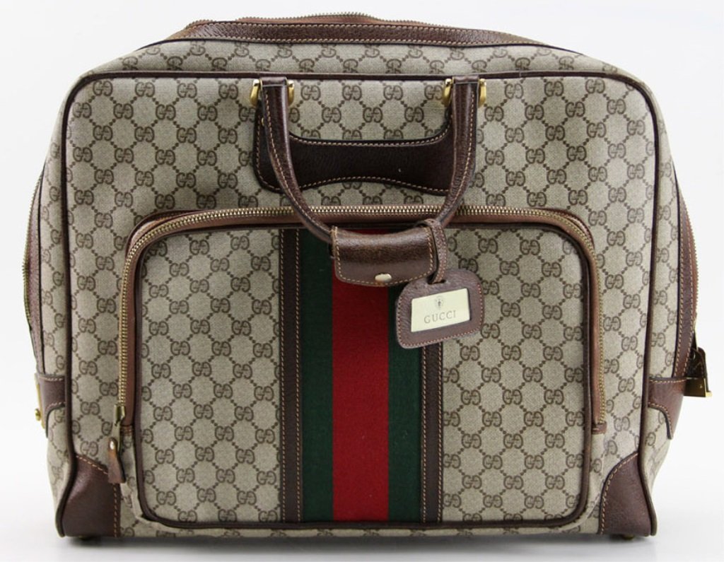 VINTAGE 1980s GUCCI TRAVEL BAG: VINTAGE 1980s GUCCI TRAVEL BAG Vintage 1980s Gucci travel bag with GG pattern fabric and green and red stripe. Zipper toggle locks into place when zipped closed. Includes a key for locking the zipper.