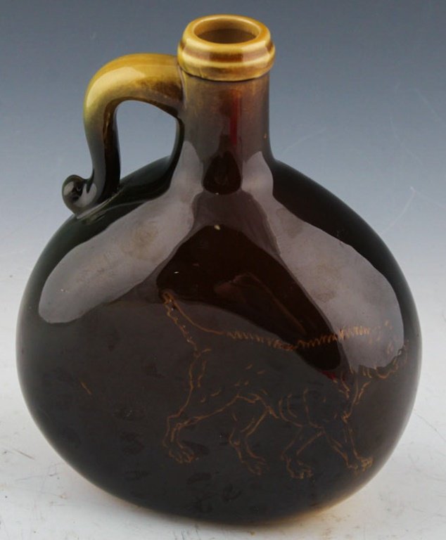 ROOKWOOD POTTERY FIGHTING DOG FLASK 1891: ROOKWOOD POTTERY FIGHTING DOG FLASK 1891 Having standard glaze and decorated with incised image of two dogs facing off over a bone, on a brown and yellow ground, marks include impressed Rookwood flame