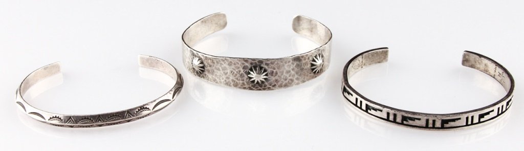 3 | NAVAJO STERLING SILVER CUFF BRACELETS: 3 | NAVAJO STERLING SILVER CUFF BRACELETS Three Navajo sterling silver cuff bracelets. Includes: 6.5mm (thickness) minimal design (1.25" opening), sunburst design (1.25" opening) with a sun and a ram