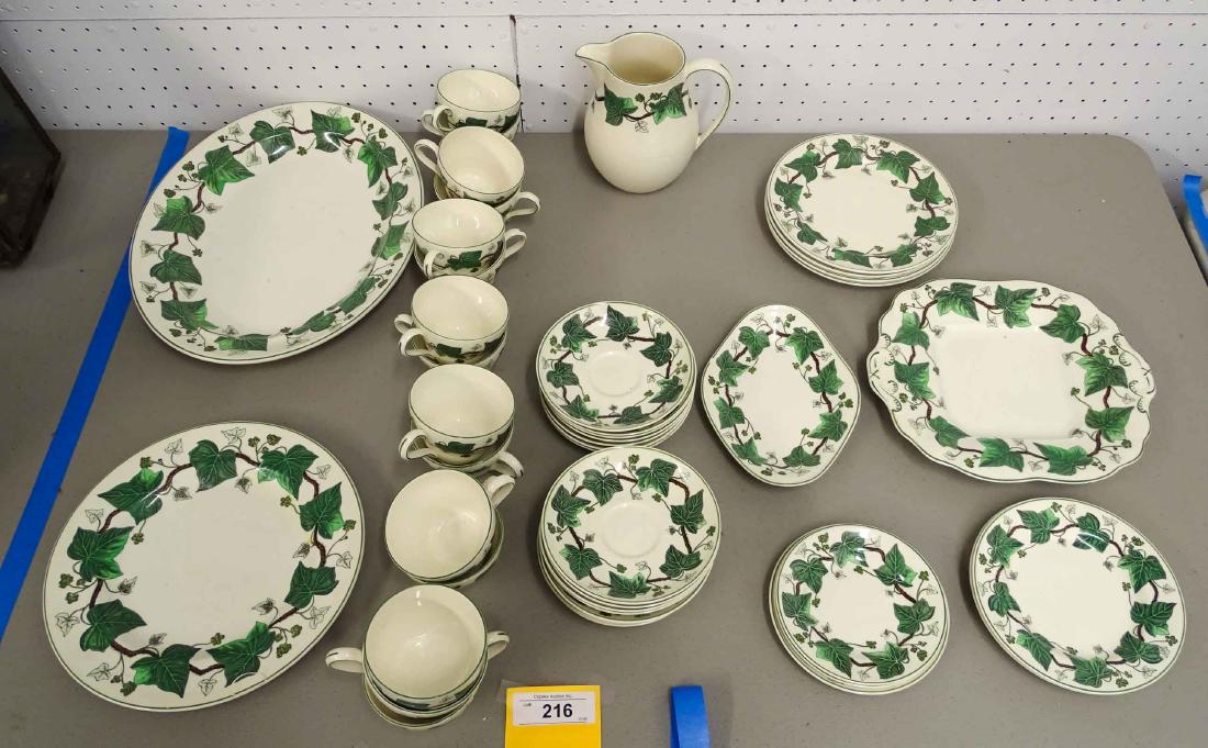 Wedgwood Lot: Wedgwood "Napoleon Ivy" dinner service. Includes (1) 10 1/2" plate, (4) 8" plates, (2) 7" plates, (3) 5 1/2" plates, (14) cups and (16) saucers, 8 1/4" milk jug, 10 1/2" x 9 1/4" platter.