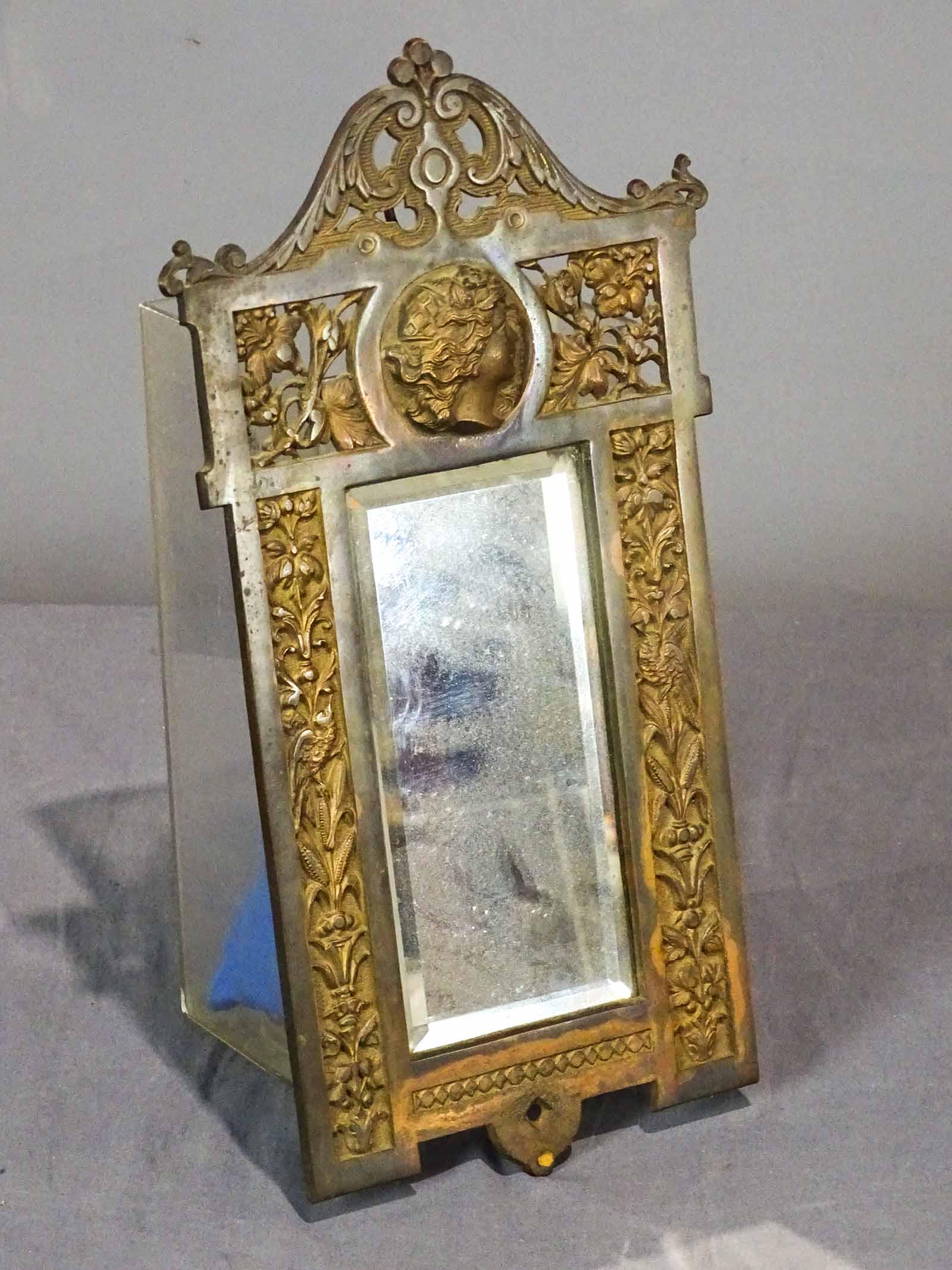 Bronze Mirror: C. 1920's bronze mirror with women's head at top. 15" x 7", beveled glass.
