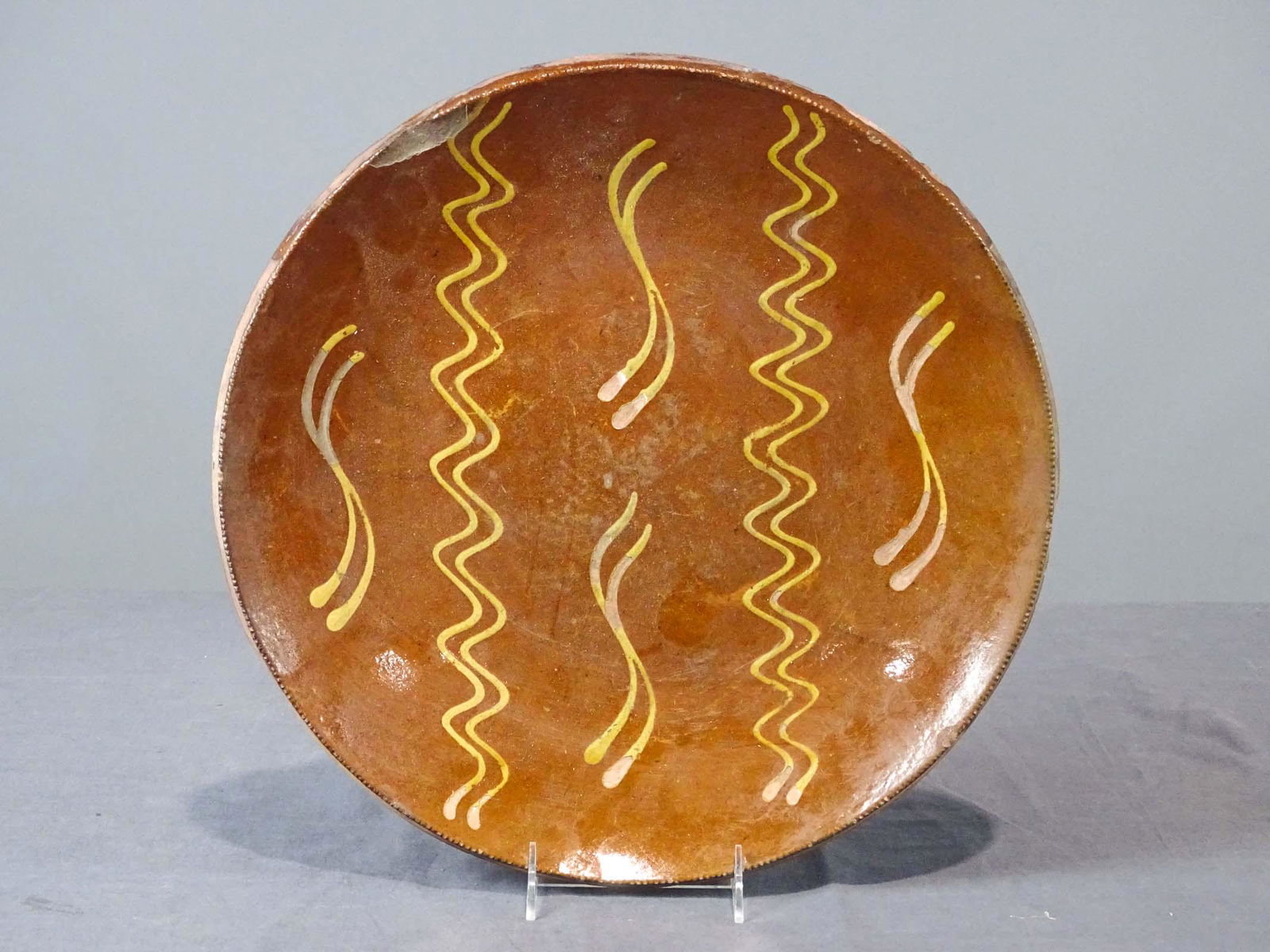 Redware Charge: Early slip glaze redware charger. 14 3/4" D.. Some imperfections.