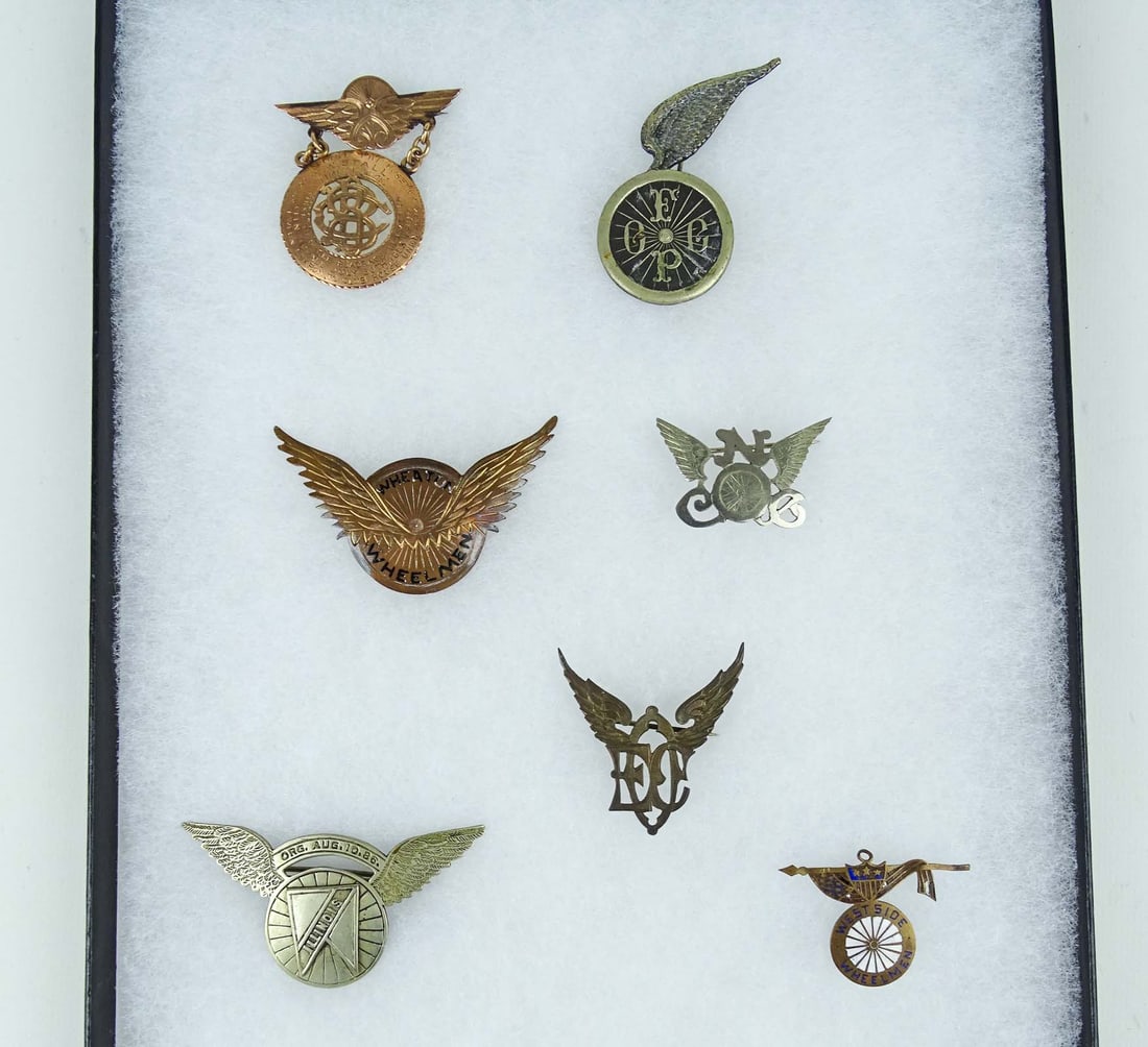 Winged Wheel Pins: Collection of (7) winged wheel club pins. Includes "First Tricycle Race in America", Wheaton, Illinois etc.. Case included. Ed Berry Collection.