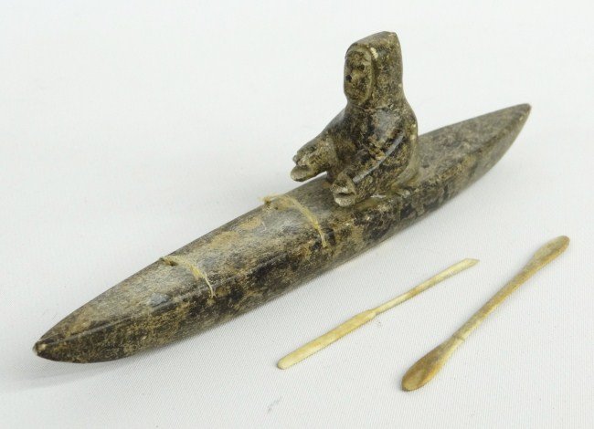 Inuit Eskimo Stone Sculpture: Inuit Eskimo stone sculpture man in kayak with bone paddle and spear. Retains original label "Canadian Eskimo Art". 8" Length.