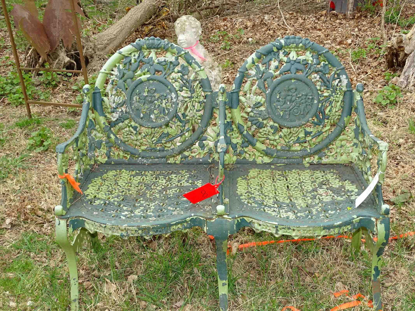 Cast Iron Garden Bench: Cast iron "double chair" garden bench with three cherubs medallion back and animal head finials. 43" W. x 16" seat Ht. x 36" Ht.. Barbara Packer Collection.