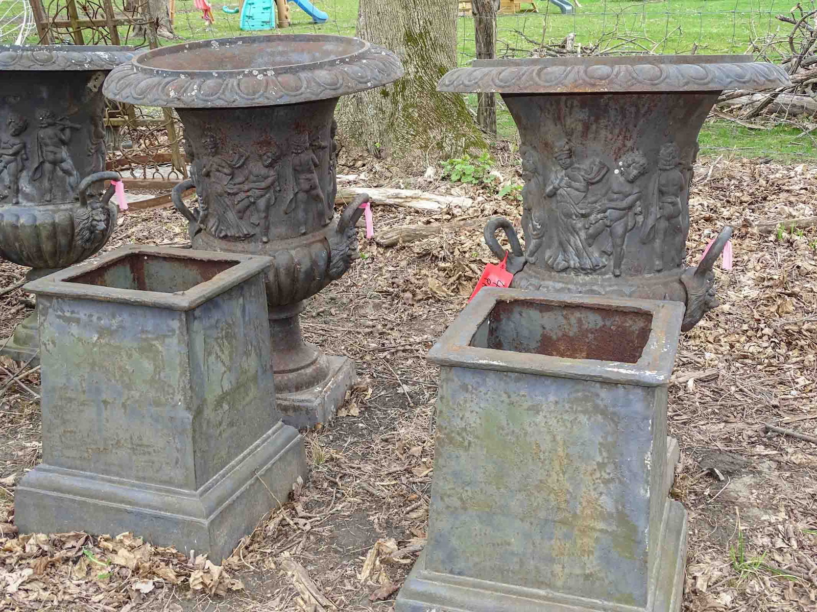 Pair of Cast Iron Urns: Pair of cast iron urns on bases with neo classical relief. 60" Ht. x 30" Dia. Barbara Packer Collection.