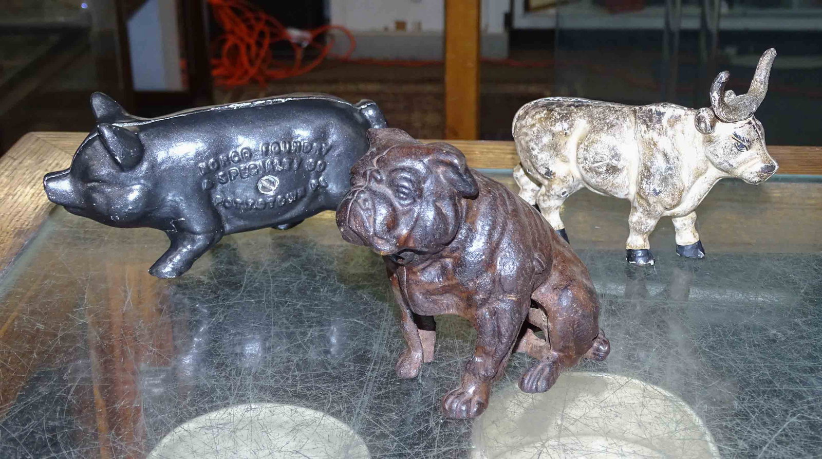 Bank Lot: Lot (3) cast iron banks including bulldog (4 1/4" Ht.), pig "BUY AT NORCO AND SAVE" (3" Ht.), bull (3 3/4" Ht.).