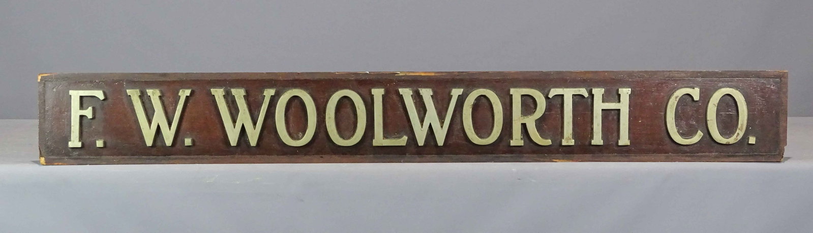 Woolworth Trade Sign: Wood and metal trade sign "F.W. WOOLWORTH CO.". Consigned from a descendant of the family. 57" x 7 1/2".