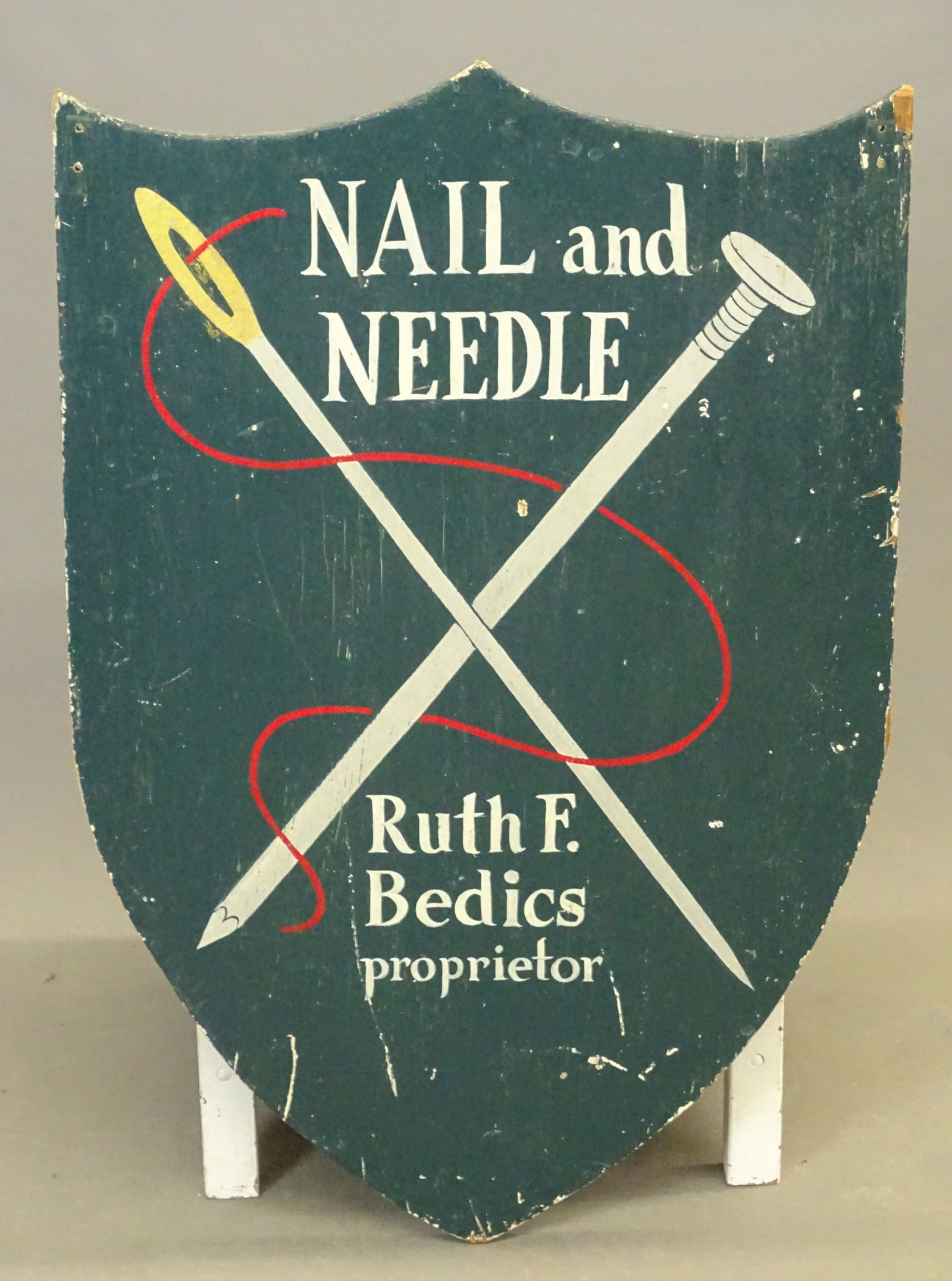 Trade Sign: Wooden painted two sided trade sign "NAIL and NEEDLE / Ruth F. Bedics proprietor". 36" x 23".
