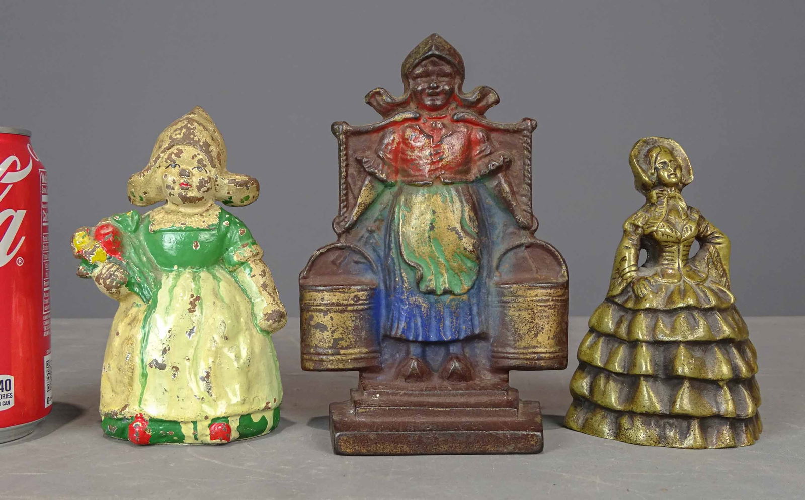 Misc. Lot: Lot including Hubley cast iron Dutch girl doorstop (5 1/4" Ht., #181 Penny Bank Book); brass "Little Colonial Lady" bell, shoes as clappers (4 3/4" Ht.), cat iron Dutch girl bookend (6 1/4" Ht.).