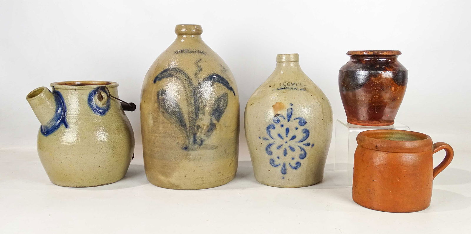 Stoneware Lot: Stoneware collection including: "F.H. Cowden Harrisburg" decorated jug, "Cortland" decorated jug, "Binghamton" swing handle crock with spout, large handled mug, 6" redware decorated pot. (5) pieces.