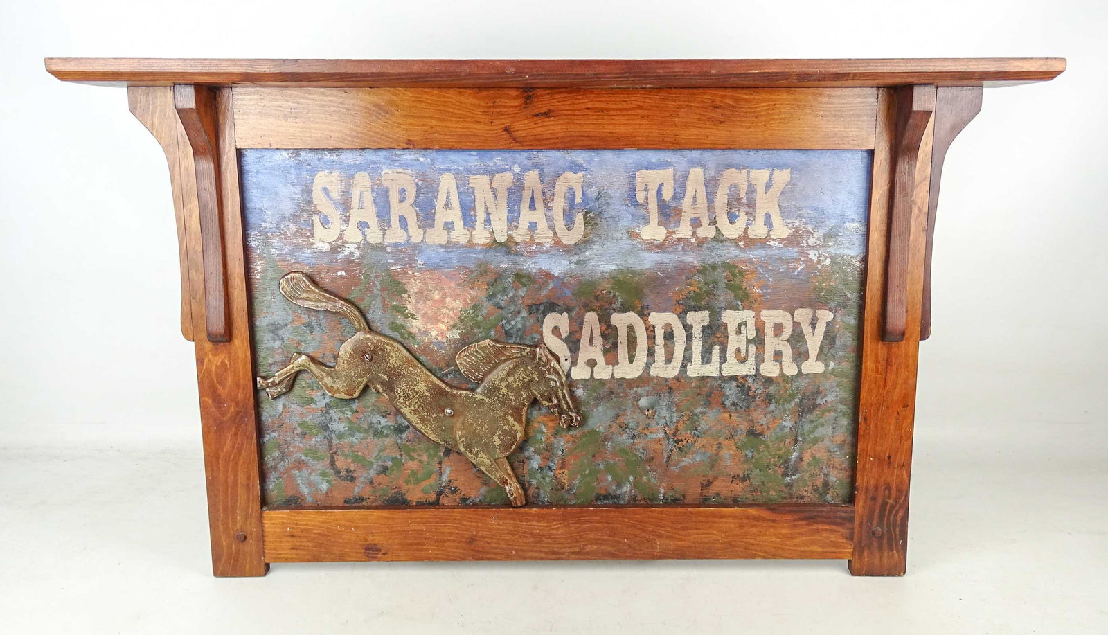 Trade Sign: Painted wooden trade sign "SARANAC TACK SADDLERY". 22" x 36".