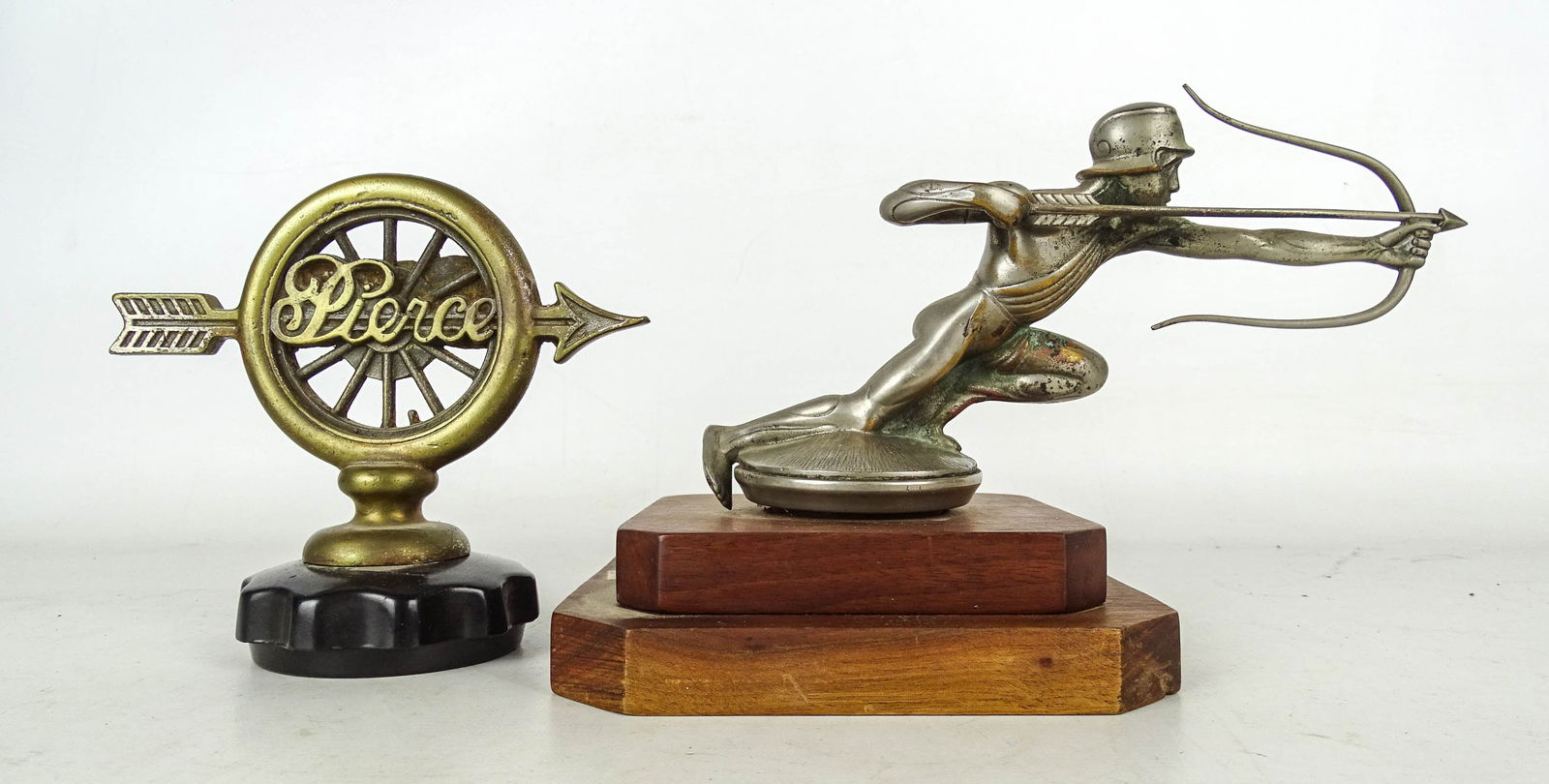 Auto Mascot Lot: Lot: 1930s Pierce-Arrow "Archer" radiator mascot on base (6" Ht, 8 1/2" L.), C. 1924 Brass radiator wheel & arrow mascot (5 1/4" Ht.).