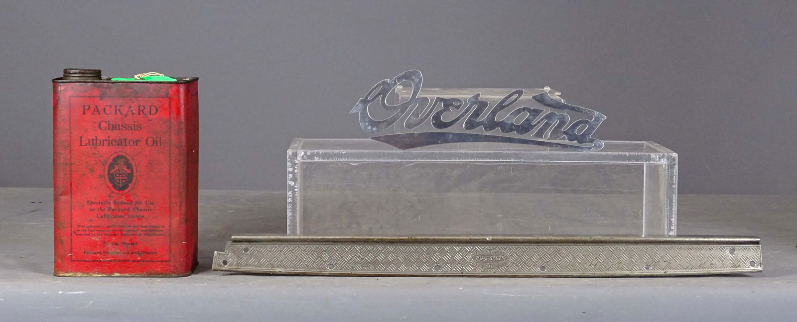 Automobilia Lot: Misc. Lot: "Overland radiator script" (12 1/2"), Marmon door sill plate (26 1/2"), and Packard chassis lubricator oil can.