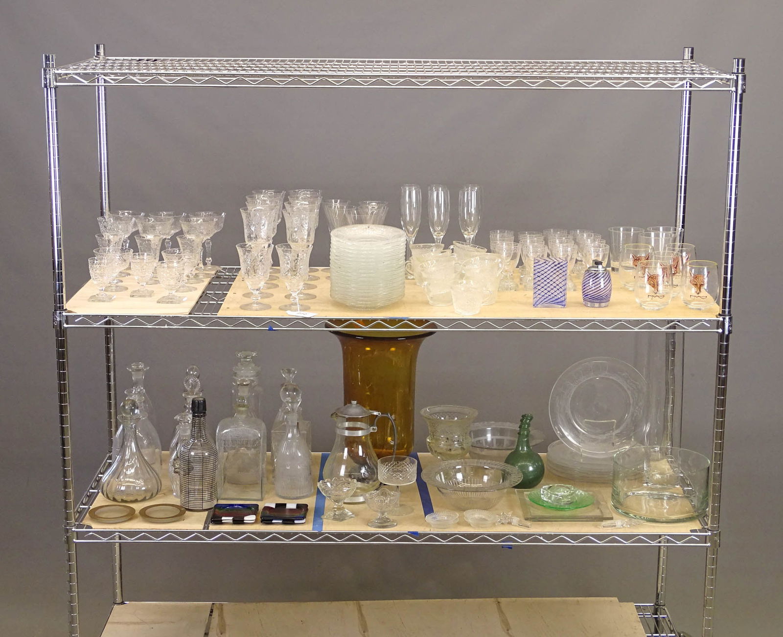Large Lot of Glassware: Large collection of glassware including Tiffany decanter, (2) decanters, sets of stemware, (12) piece Sandwich set, large Amerber vase (15 3/4" Ht.) and more. Approx. 100 pieces.