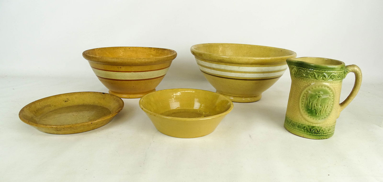 Yelloware Collection: Yelloware collection (5 pieces): (3) bowls (largest 13" dia), plate (9 1/4"), and pitcher (6 3/4" Ht).
