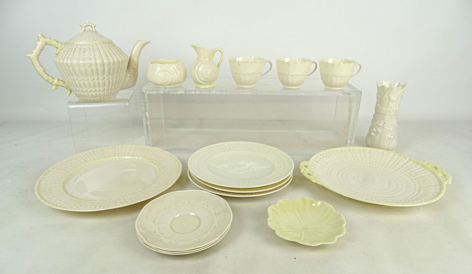 Irish Belleek Porcelain Lot: Irish Belleek porcelain lot: Teapot, (3) cups and saucers, (3) 8" plates, 10 1/2" plate, 9 3/4" handled plate, sugar and creamer, 4 3/4" shaped plate, vase "Lily of the Valley" (6 1/2' Ht.).