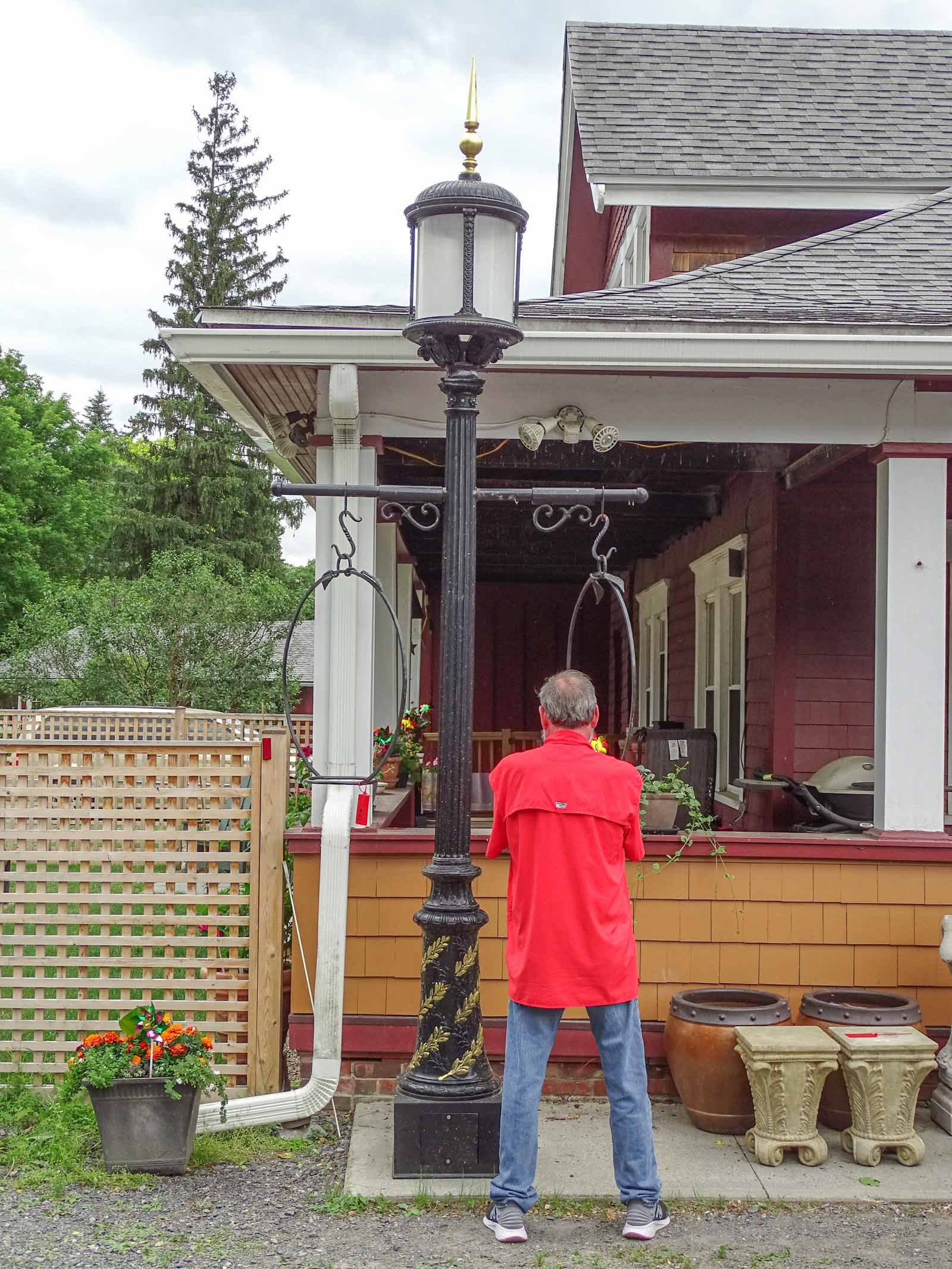 Wrought Iron Lamp Post: Impressive heavy iron lamp post with finial top. Made to be electrified. Base 15" D., Approx. 12' Ht.. Features side rings.