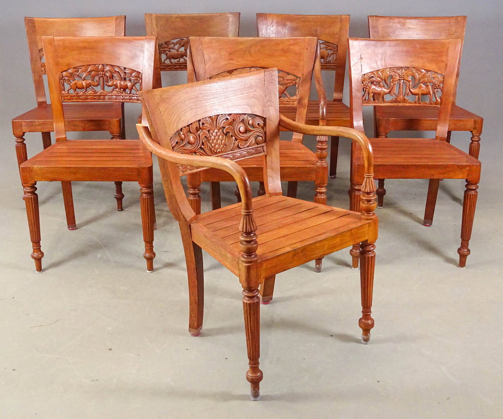 Set of Teak Chairs: Set of (8) carved teak chairs. Animal motif on back-rests. 18 1/2" seat Ht., 34" overall Ht.. One has rear arm that needs repair.