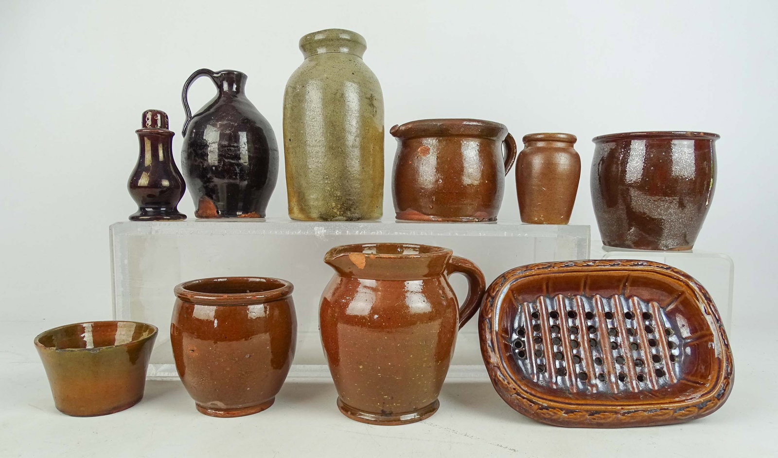 Redware Lot: Redware pottery lot including: 6 3/4" jug, (2) pitchers, large Bennington soap dish (8" x 5 1/2"), salt shaker (4 1/2"), stoneware jar (7 1/2" Ht.), (4) misc. jars. (10) pieces. Imperfections.