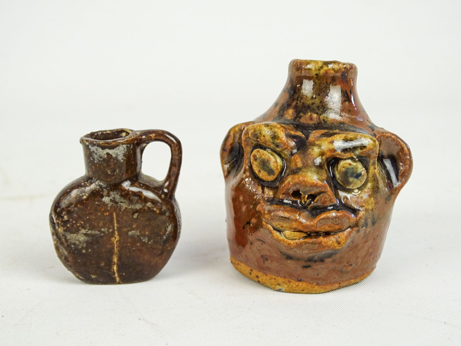 Marie Rogers Face Jug: Lot including: Marie Rogers miniature face jug (2 1/4" Ht.), miniature jug (1 1/2" Ht.).