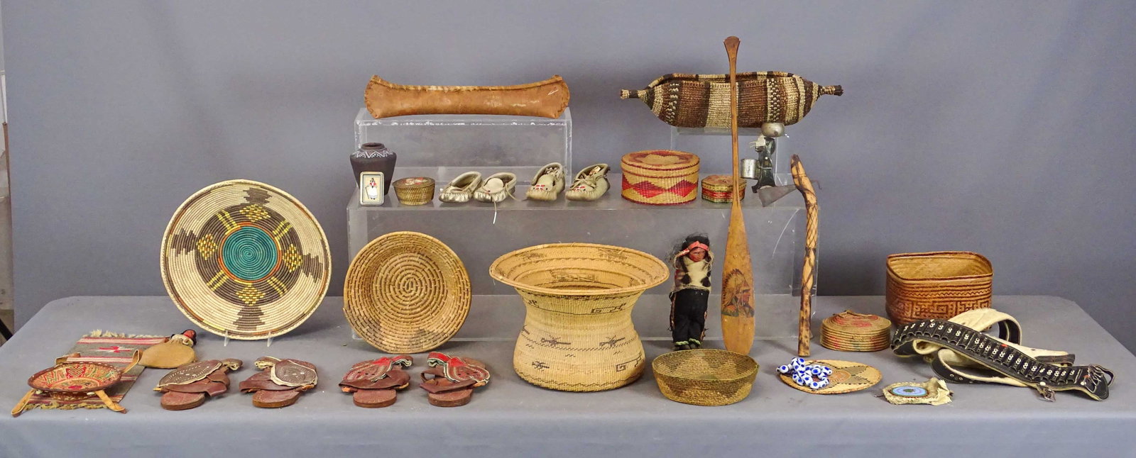 Native American Lot: Lot of varioius Native American baskets (largest 14" D.), doll, wooden painted paddle (27 1/2" L.), axe (17" L.), pottery jar, mat, belt, sandals, birch canoe (18" L.), etc..