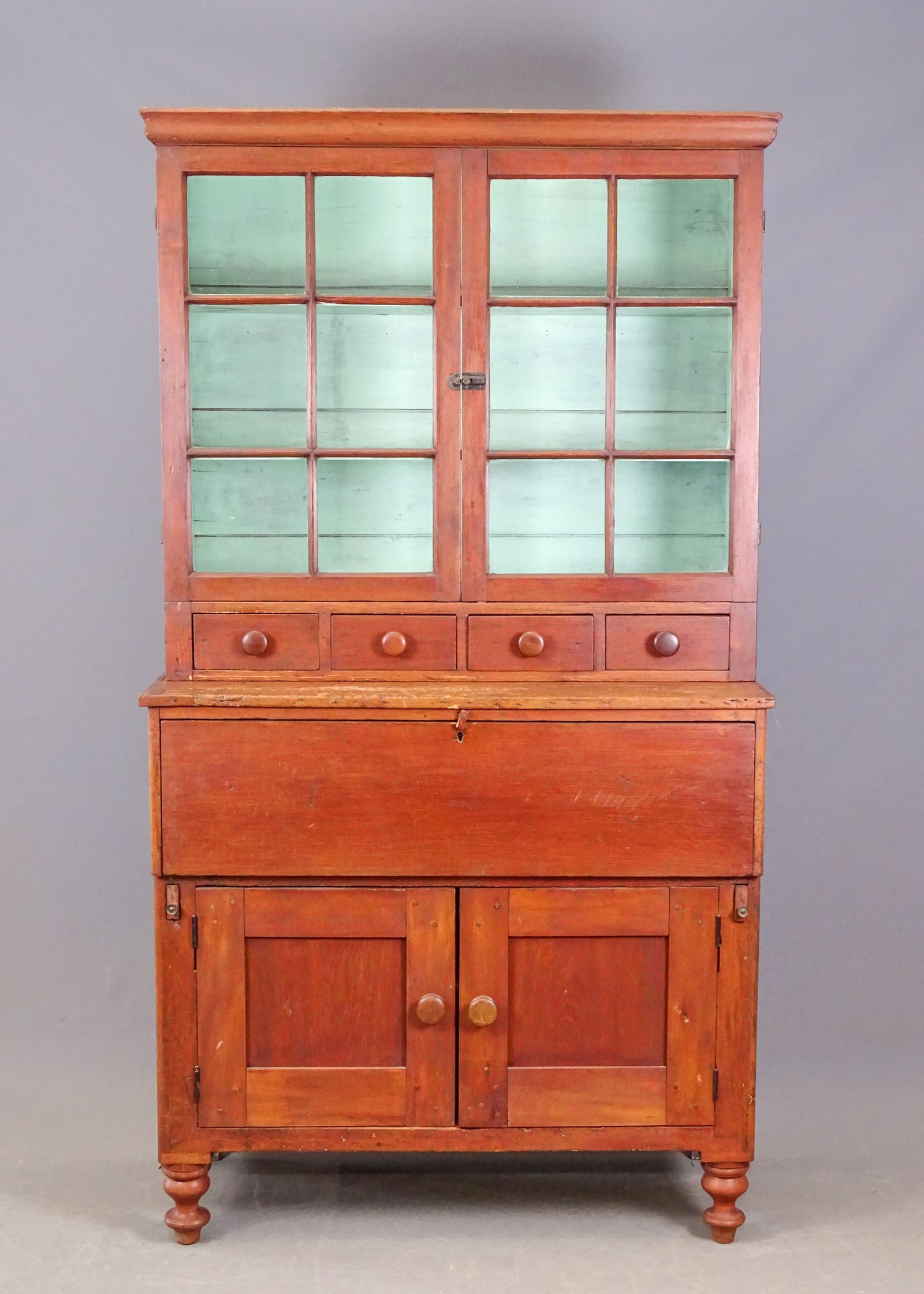 19th c. Wall Cupboard: 19th c. two part wall cupboard in old red wash. Top has (2) 6 pane glass doors with (4) drawers, base with desk section over doors. 42" x 19" x 80" Ht..