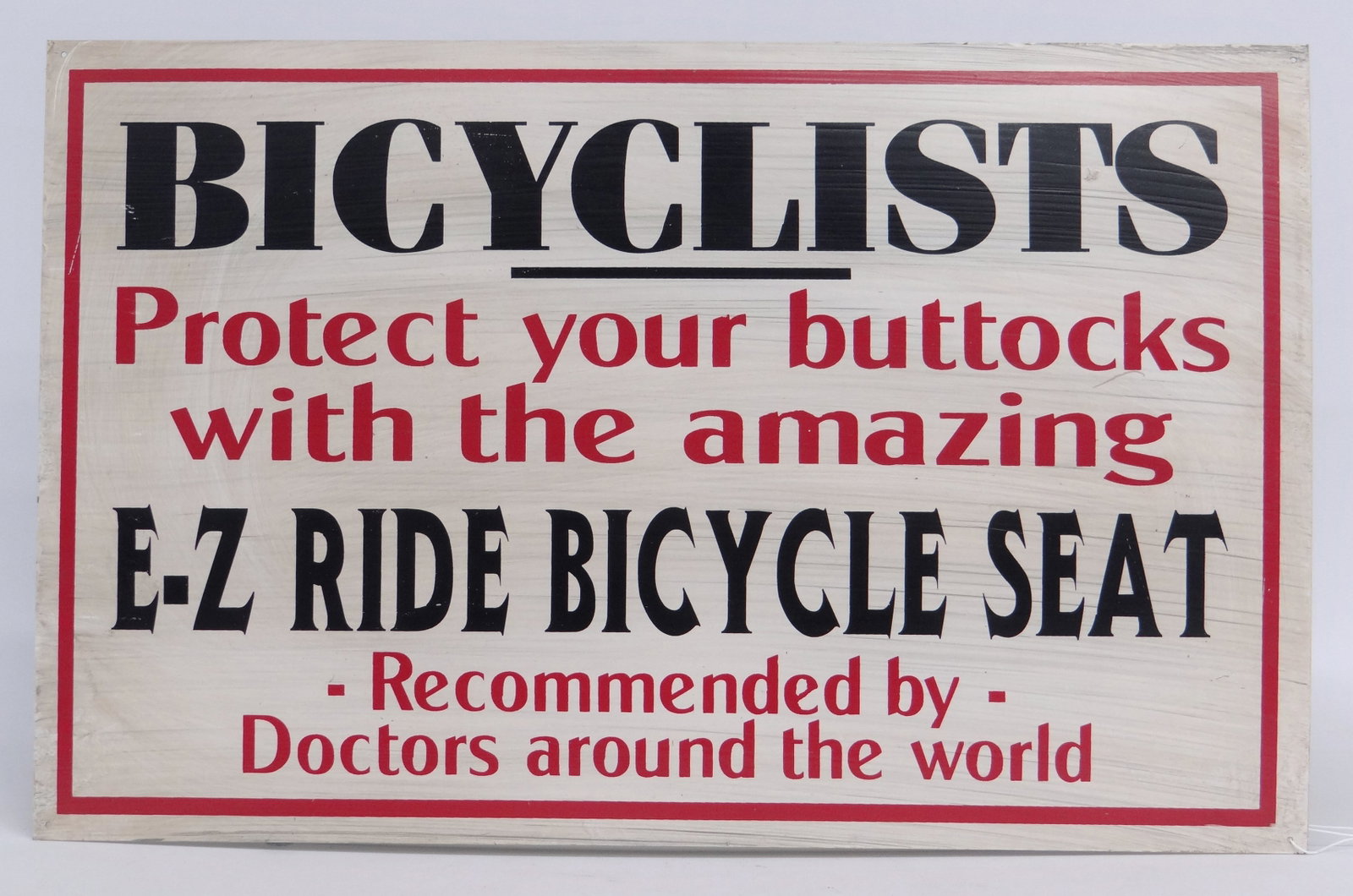 Tin Bicycle Sign: Tin bicycle sign "Bicyclists Protect you buttocks with the amazing E-Z Ride Bicycle Seat....", 14" x 22". Good condition. David Metz Museum. Previously sold at Copake Auction April 2014, lot 470.
