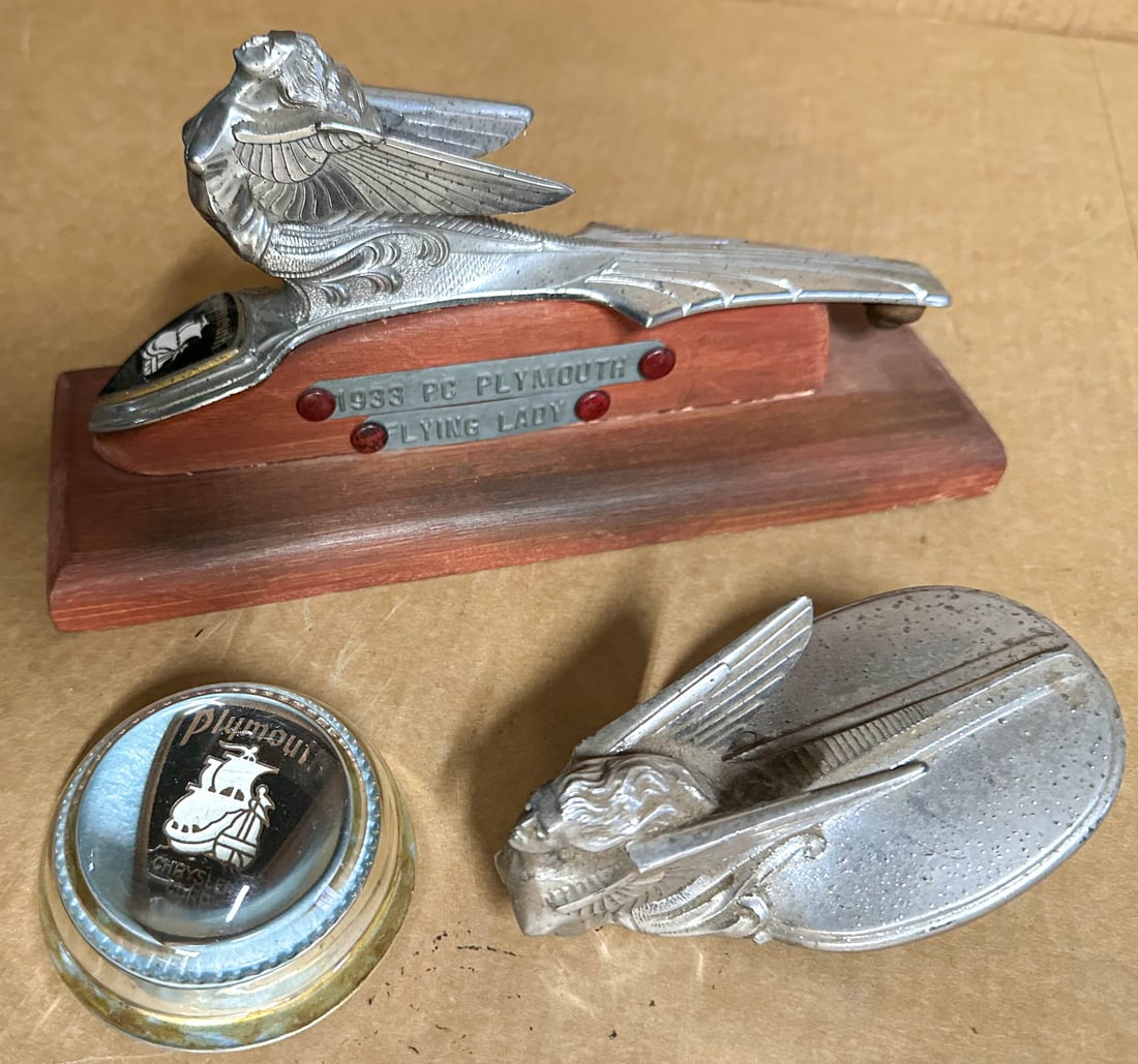 Plymouth Lot: Plymouth items 1931-32 radiator cap mascot, 1933 fixed hood mascot and grill badge paperweight.