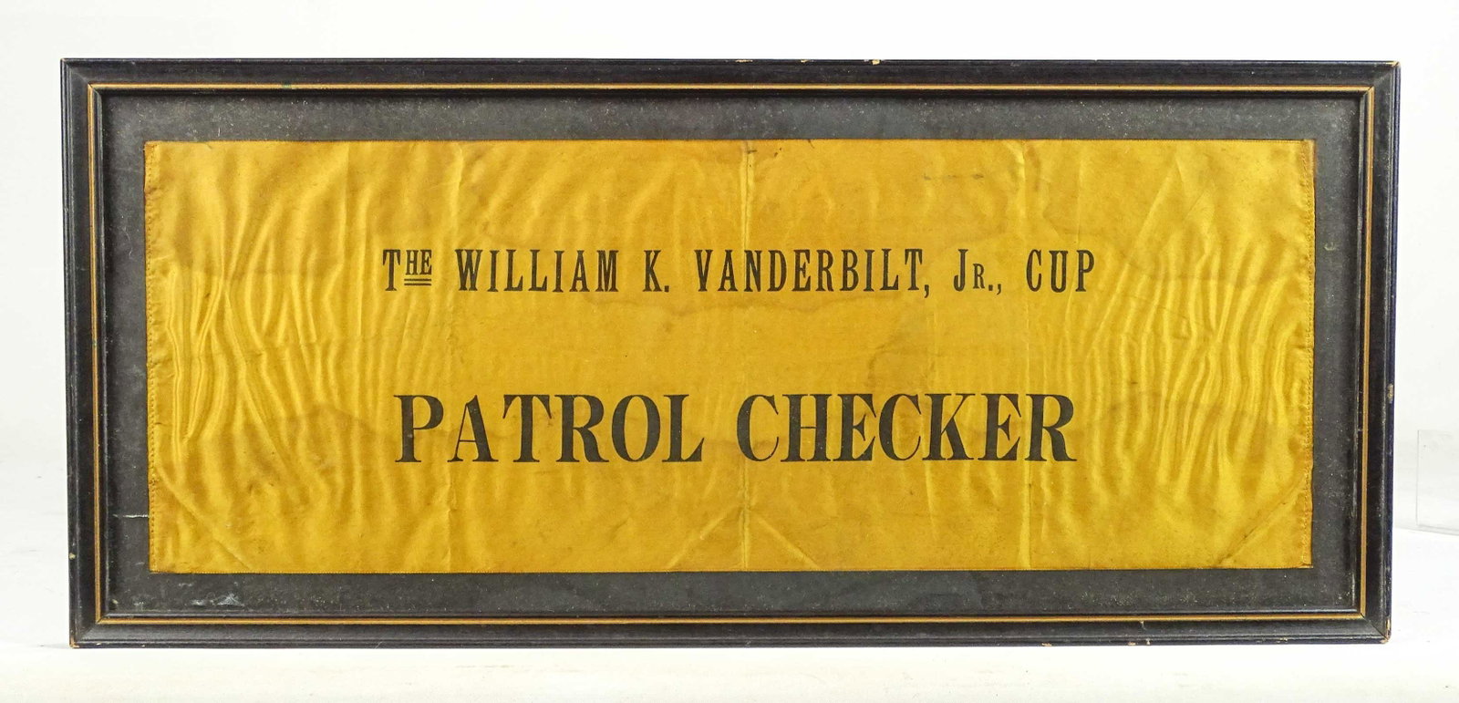 Vanderbilt Race Arm Band: 1906 Patrol Checker Vanderbilt race arm band in frame. Overall in frame. 9" x 19 1/2". Fair condition.