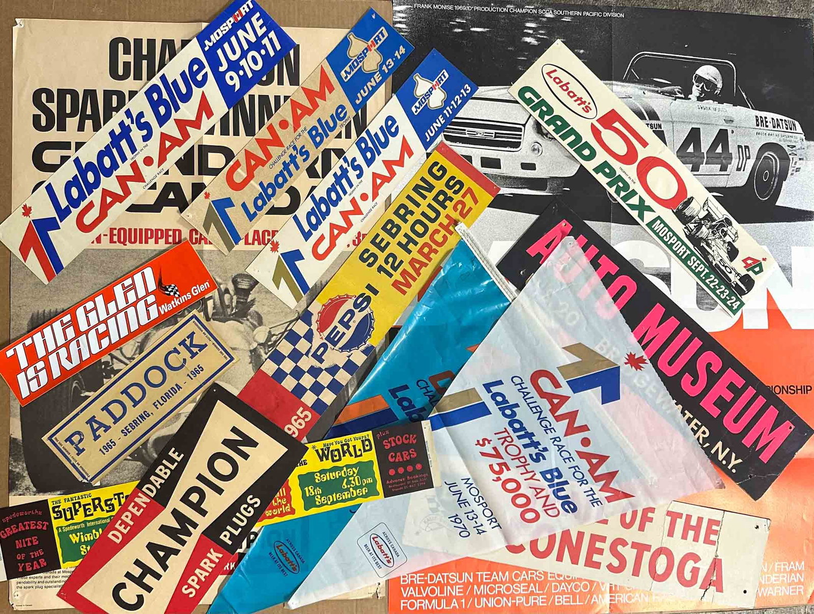 Racing Lot: 1960's Canadian Grand Prix, Sebring, other race items - 1967 Canadian GP poster, 30 x 19, Datsun BRE poster 33 x 24, various bumper stickers, small posters, etc two hanging triangles, 15 x 24 each.