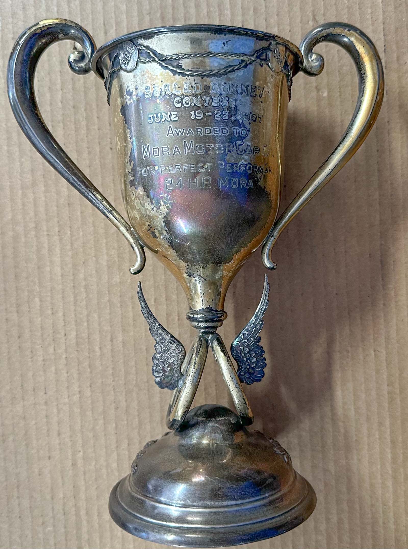 Auto Club Trophy: 1907, June 19-22, Auto Club of America trophy, "Sealed Bonnet Contest - Awarded to Mora Motor Car Co, Perfect Performance, 24 HP Mora", 12 inches high.