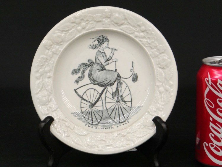 Boneshaker Plate: 19th c. Transferware 6 1/2" Dia. Ironstone plate "The Summer Style" depicting a lady on a boneshaker playing a penny whistle. Good condition.