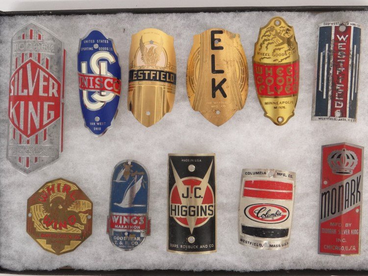 Head badge Collection: Collection (11) head badges including: Monark :Silver King", US "Unisco", "Westfield", Whirl Wind", Wings Marathon", "J.C. Higgins", "ELK", "Wheel Goods Flyer", "Columbia", "Westfield", "Monark". Good