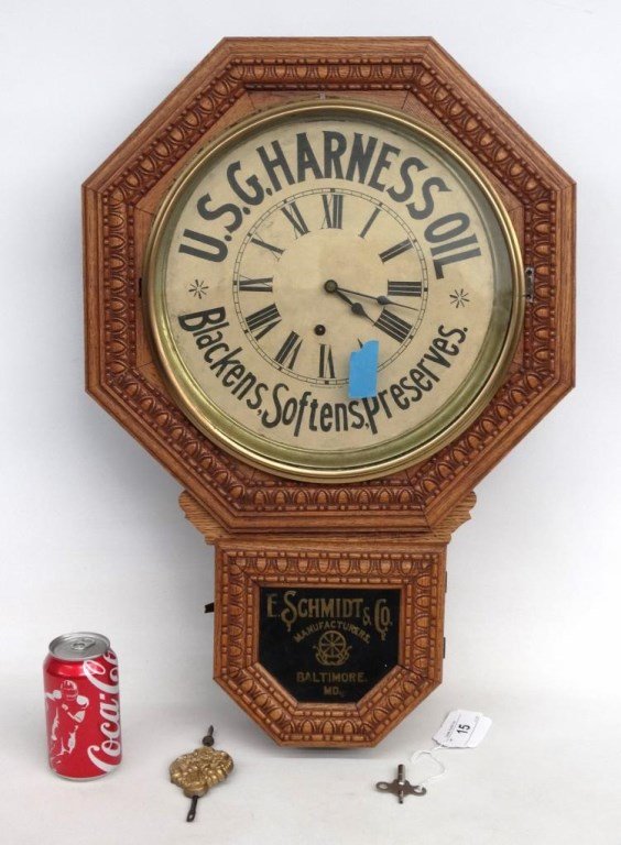 19th c. Advertising Wall Clock: 19th c. oak advertising wall clock "U. S. G. Harness Oil...". E. Schmidt & Co., Manufacturers, Baltimore. MD.". Bezel loose and needs to be reattached. Retains pendulum and key. 17 1/2" W., 25" Ht..